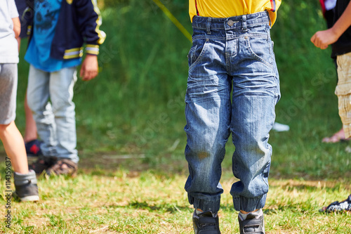 Small boy in blue jeans jumping in front of a group of children,