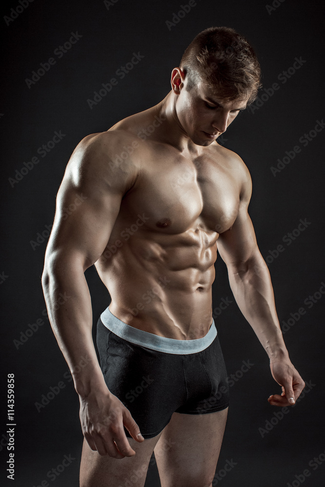 Muscular bodybuilder guy doing posing over black background