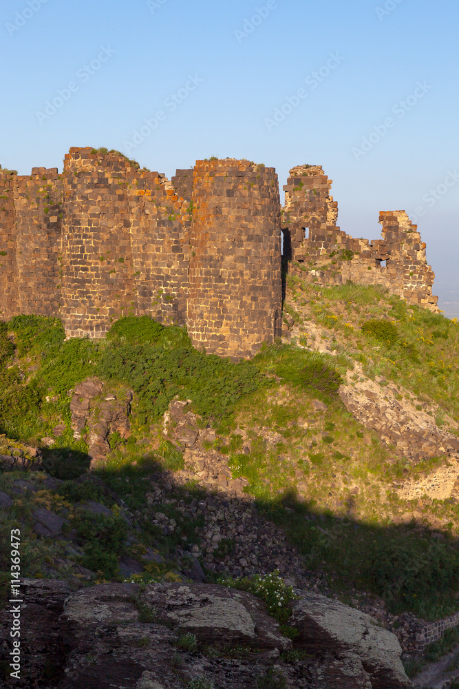 Amberd Fortress with ruined walls on green hill in Armenia