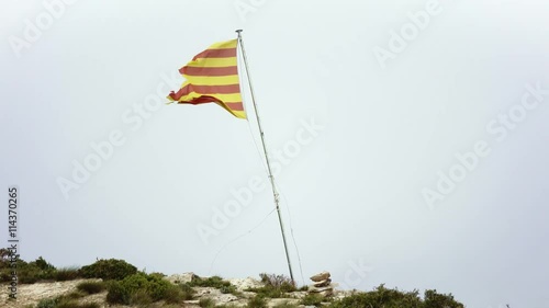 Wind blows on old ripped catalan flag in pyrineos mountains top. Thick fog and clouds go very fast and low photo