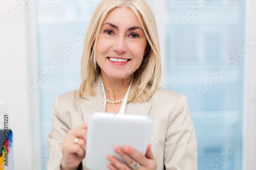 Mature businesswoman using a tablet in her office