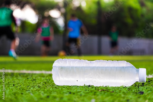 Plastic bottle of water on artificial grass of football field 
