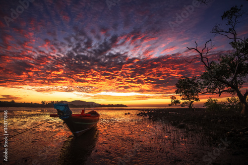 Thai fishing boat used as a vehicle for finding fish in the sea at sunrise photo