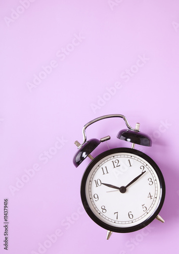 A black alarm clock on a pink background forming a page border