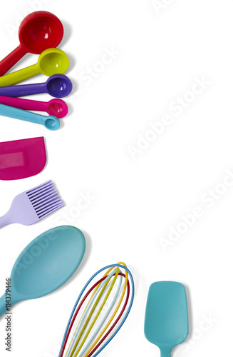 Cooking utensils - a selection of colorful silicone baking spoons, spatulas, whisk, measuring spoons and a pastry brush isolated on a white background forming a baking themed page border