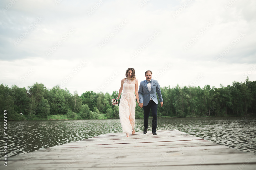 Wedding couple, bride, groom walking and posing on pier