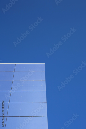 Detail of a contemporary building with glass facade and blue sky