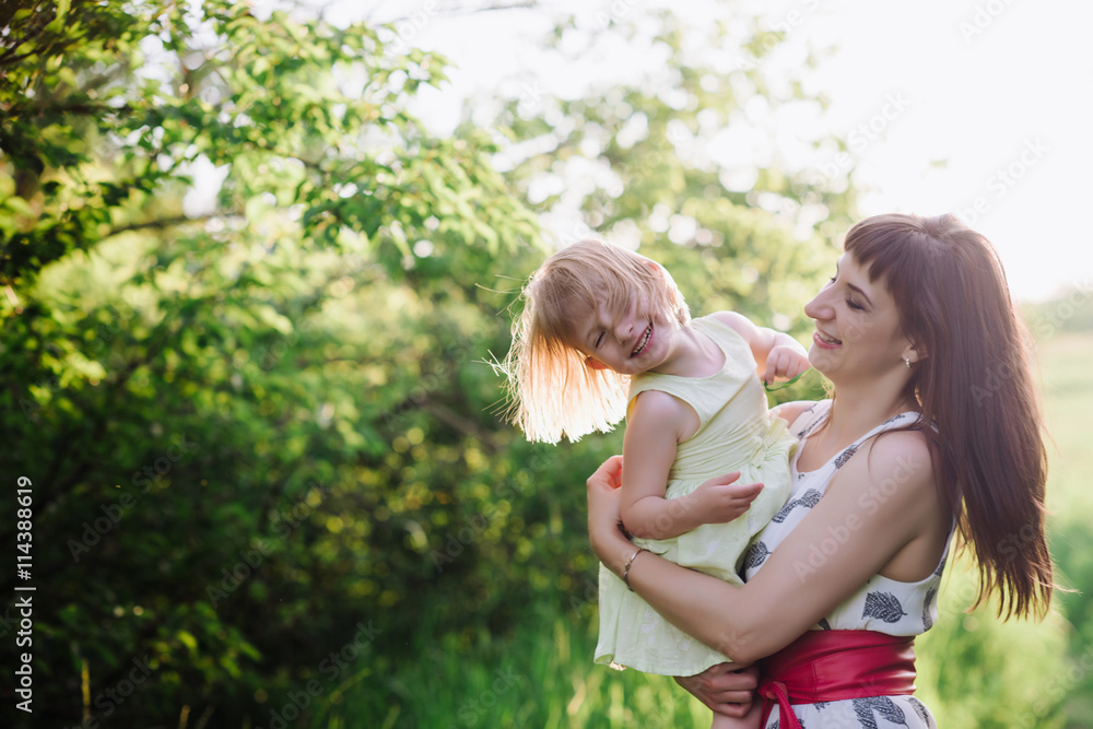 Mom kisses and hugs daughter on nature, family, motherhood, child Mom kisses and hugs daughter on nature, family, motherhood, child
