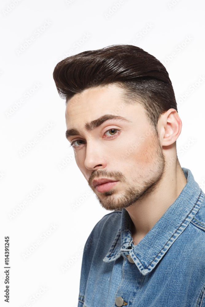 Fototapeta premium Portrait of handsome man in jeans shirt demonstrating modern hairstyle concept in studio. Male with bright black hair. Hairdressing concept. Studio shot.