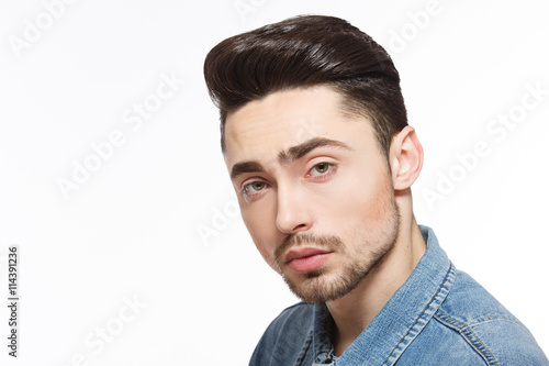 Handsome model man posing over white background demonstrating his black hair forfashion magazine in studio. Modern hairstyle concept.