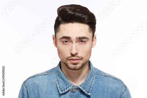 Portrait of handsome man in jeans shirtshowing his modern hairstyle isolated on white background. Male with short black hair in studio.