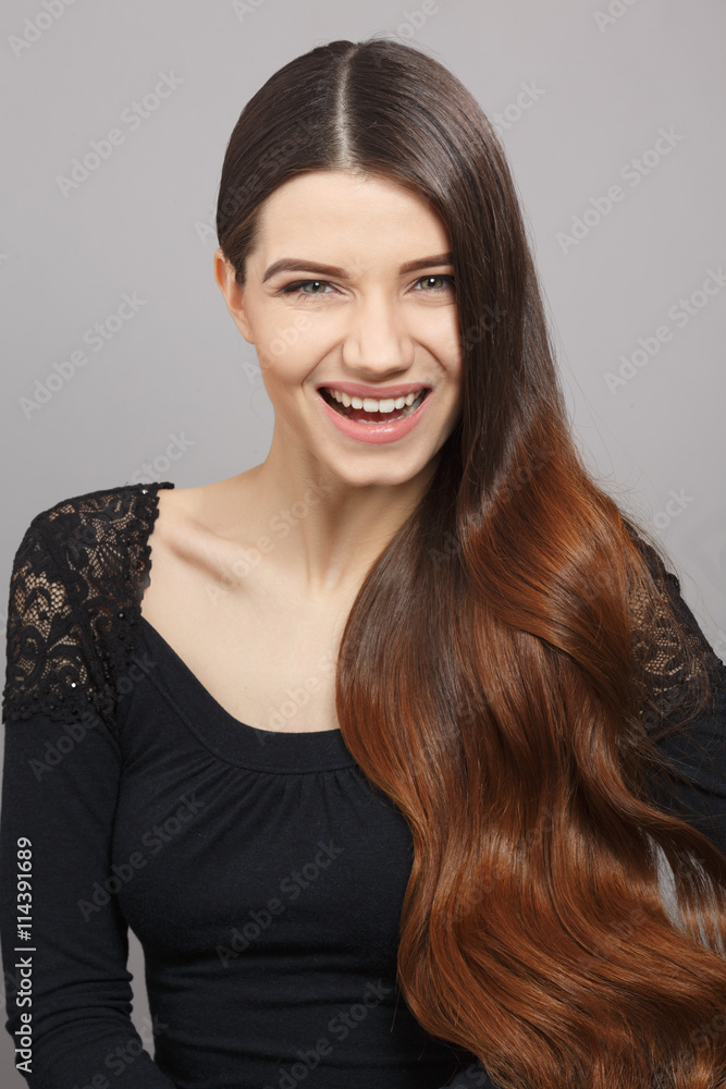 Happy model woman showing her gorgeous brown hair to camera while posing in studio. Toothy smiling beautiful female looking at camera. Happy model woman showing her gorgeous brown hair to camera while posing in studio. Toothy smiling beautiful female looking at camera.