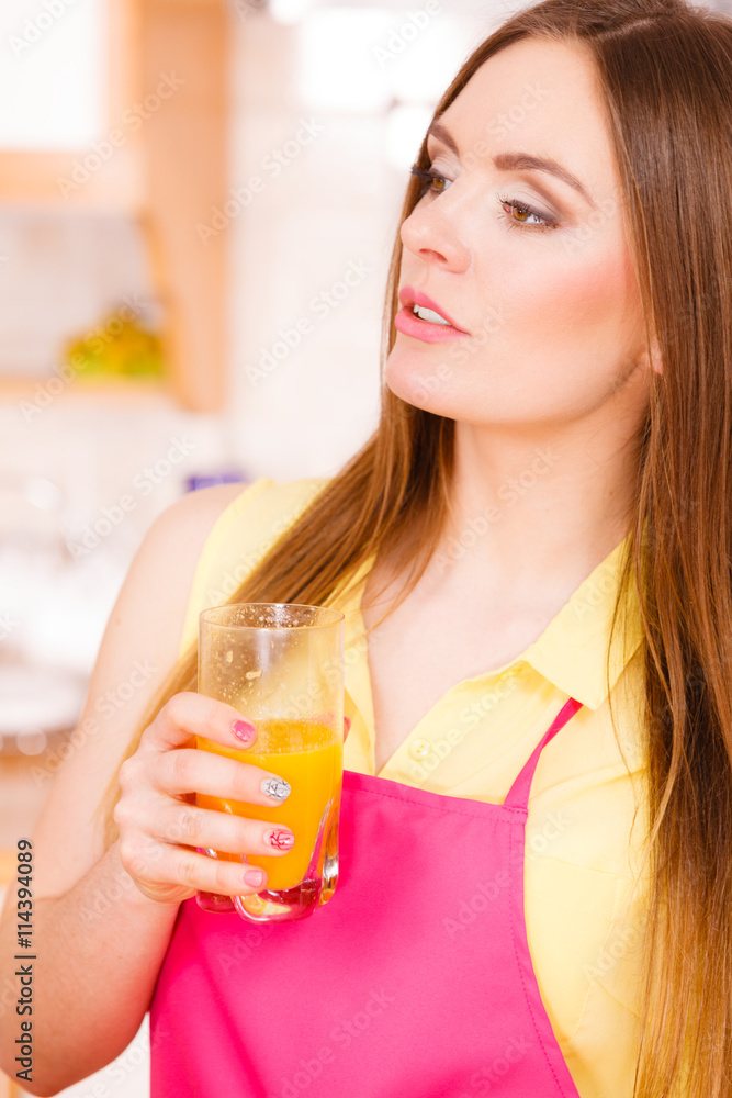 Woman in kitchen drinking fresh orange juice Woman in kitchen drinking fresh orange juice