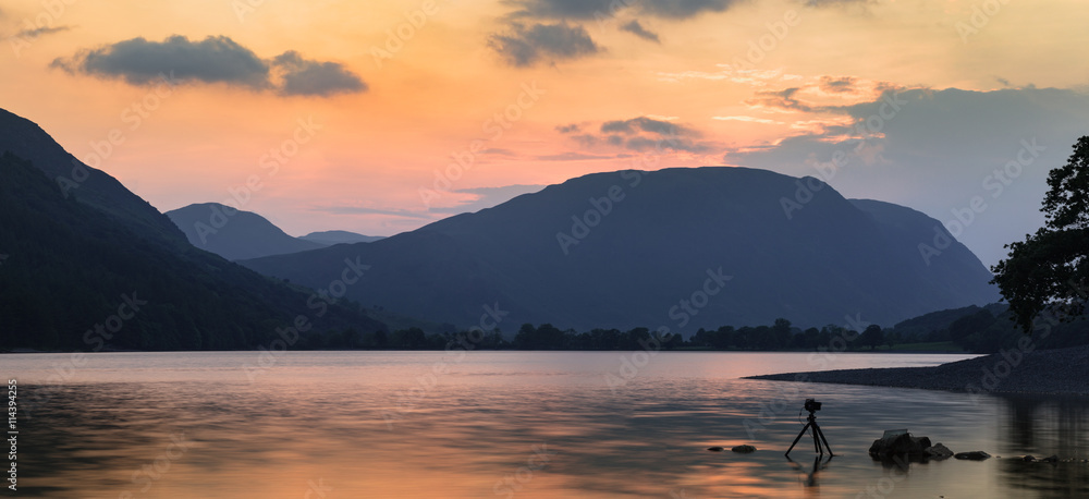 Silhouette of Photography Camera on Tripod Dipped in Water on Colorful Twilight Background