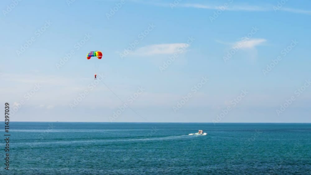 Video 1920x1080 - Tourist, dangling below a cheerful, rainbow colored parachute, being towed by a speedboat, descends for a landing in the calm, tropical sea. Video 1920x1080 - Tourist, dangling below a cheerful, rainbow colored parachute, being towed by a speedboat, descends for a landing in the calm, tropical sea.