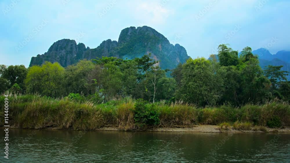 1920x1080 video - Left to right panning shot of the far bank of Nam Song River with steep rocky mountains in the background in Vang Vieng, Laos. 1920x1080 video - Left to right panning shot of the far bank of Nam Song River with steep rocky mountains in the background in Vang Vieng, Laos.