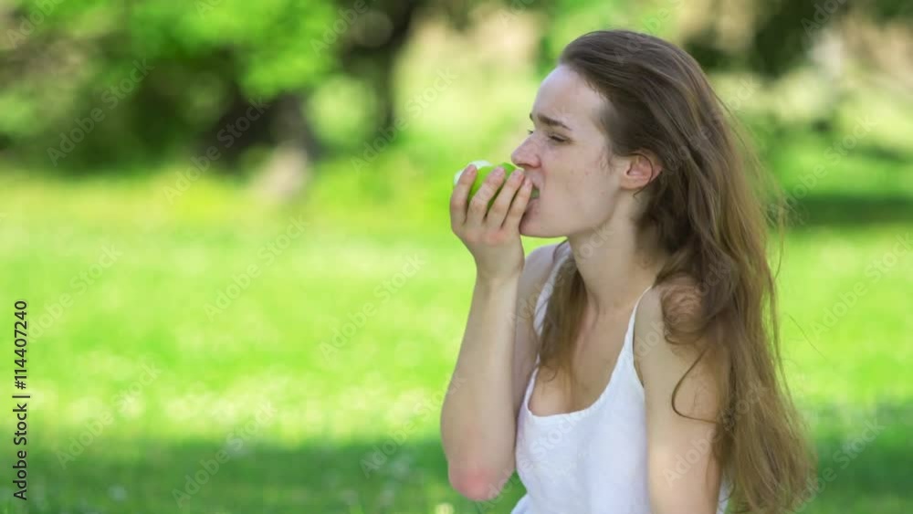 Young woman biting and eating tasty green apple Young woman biting and eating tasty green apple