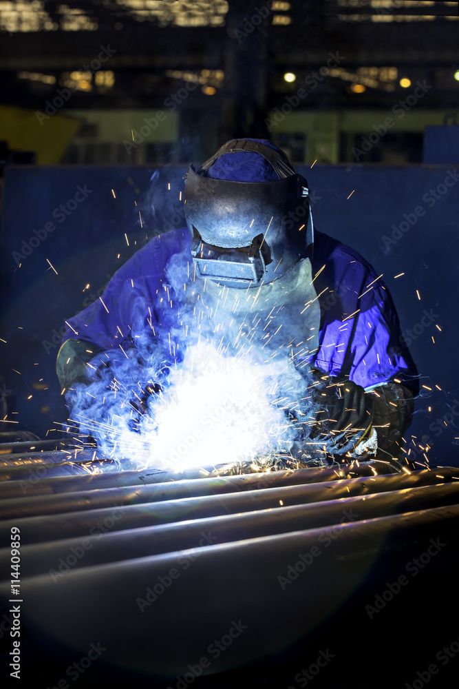 Worker dressed in protective uniform welding metal frame Worker dressed in protective uniform welding metal frame