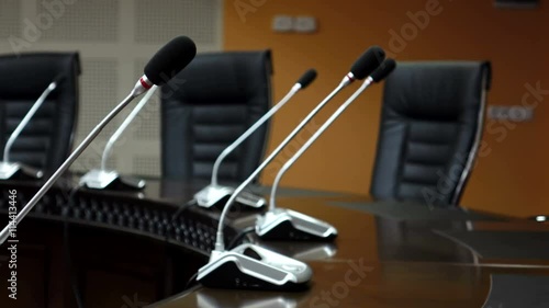 Dolly shot of microphones in modern conference room. Shallow DOF