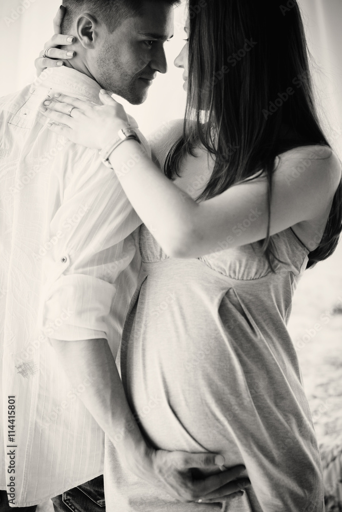 Expecting young woman leans to man's shoulder while he hugs her Expecting young woman leans to man's shoulder while he hugs her