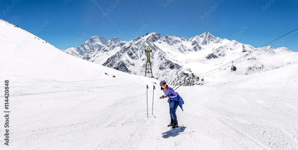 Woman hiking on sunny winter day in mountain landscape. Female hiker in warm bright outfit clothes enjoying trail walk on snow covered track.