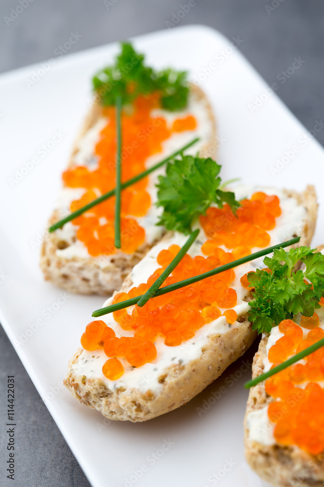 Red caviar on bread on white plate. Red caviar on bread on white plate.