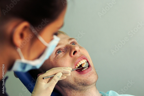Dentist examines the patient s teeth. Female dentist  male patient.