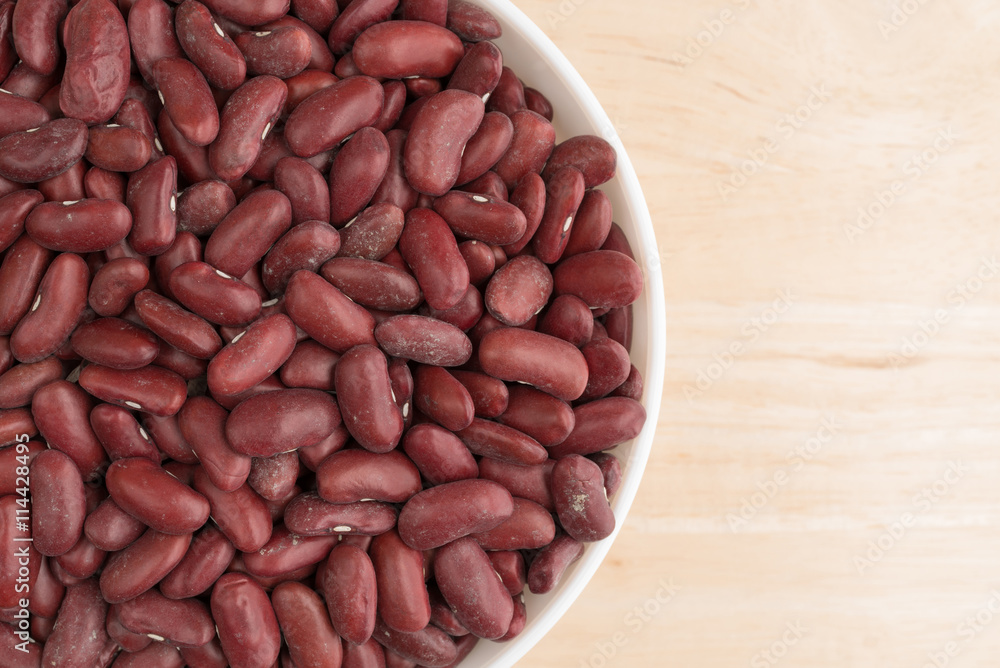 Bowl filled with dark red organic kidney beans top close view on a wood table. Bowl filled with dark red organic kidney beans top close view on a wood table.