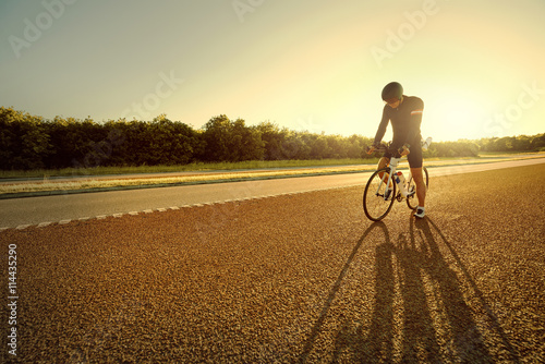 Bicyclist pausing with long shadow from sun