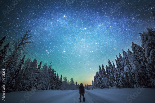 Rear view of man standing on snowy landscape against starry sky