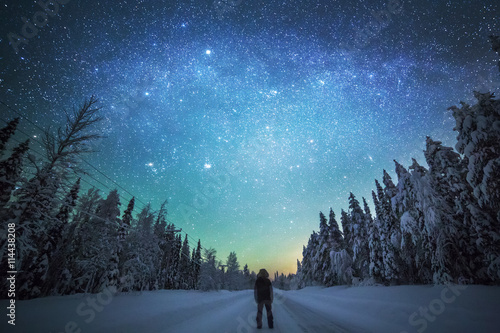 Rear view of man standing on snowy landscape against starry sky photo