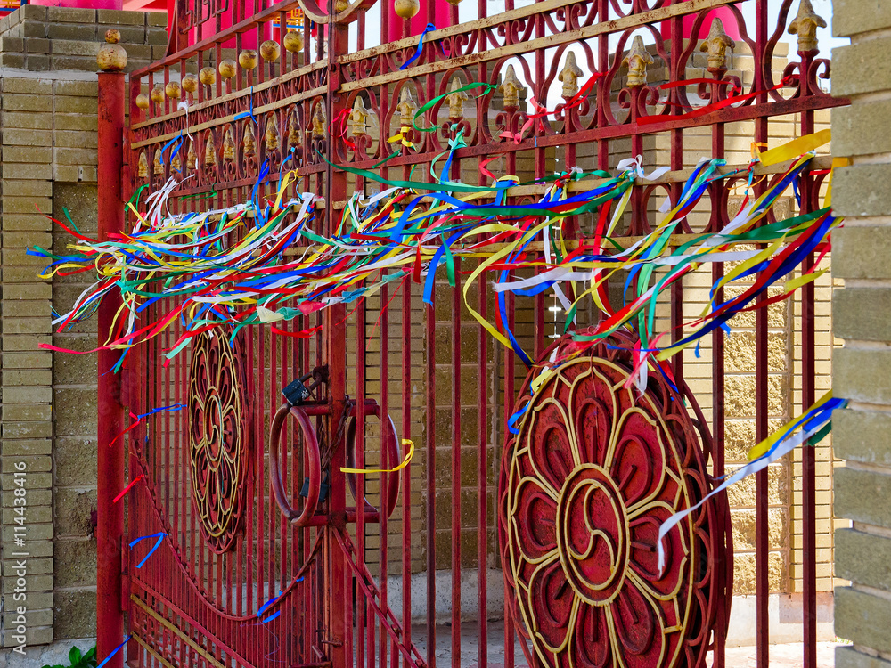 the magnificent gate of the Palace of the Buddha of red color is decorated with carved roof waving in the wind colored ribbons
