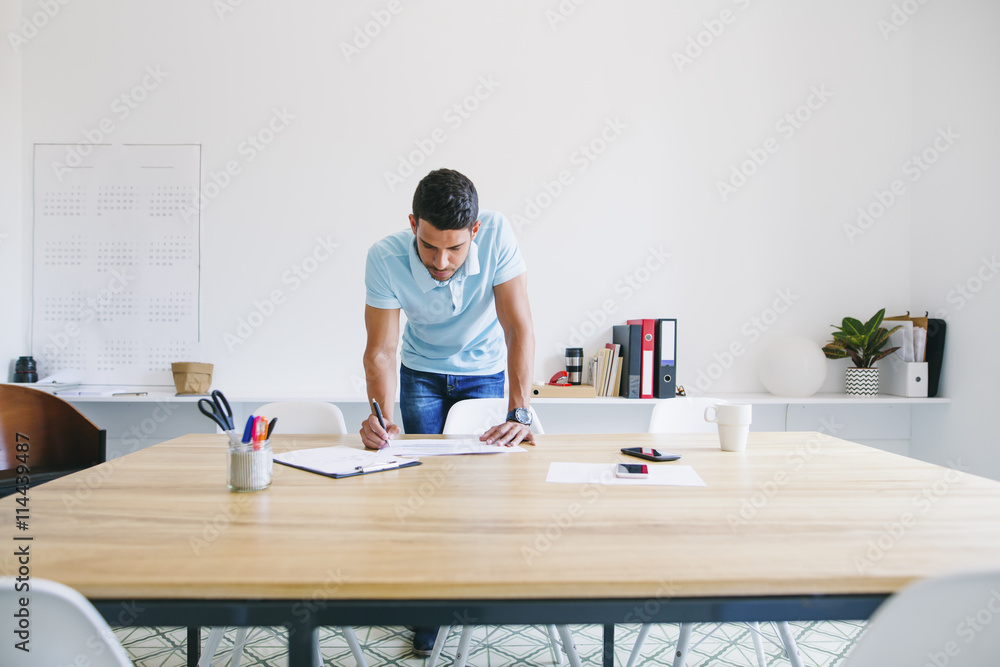 Young businessman standing at desk looking trough files Young businessman standing at desk looking trough files