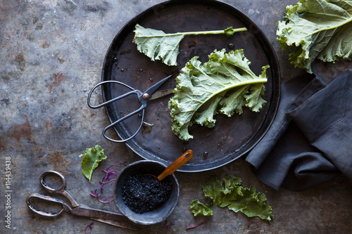 Overhead view of leafy vegetables and a bowl of black salt  photo