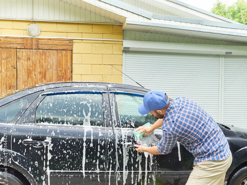 Man washing his black car near house. Man washing his black car near house.