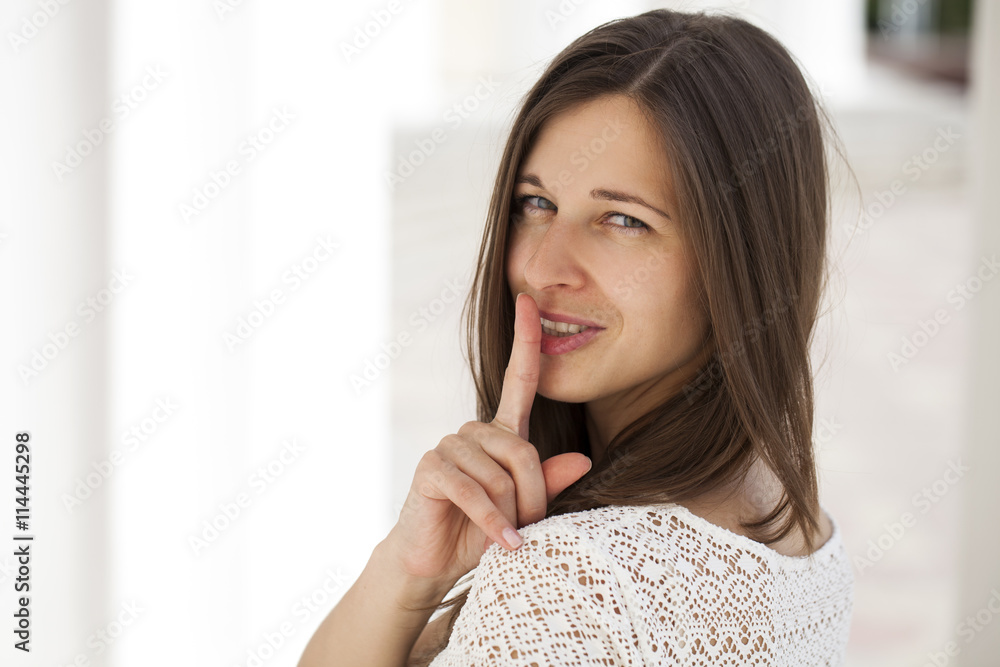 Young beautiful brunette woman has put forefinger to lips as sig Young beautiful brunette woman has put forefinger to lips as sig
