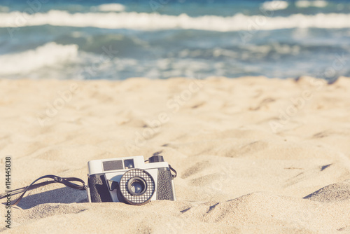 Old vintage camera lying in the sand on the beach