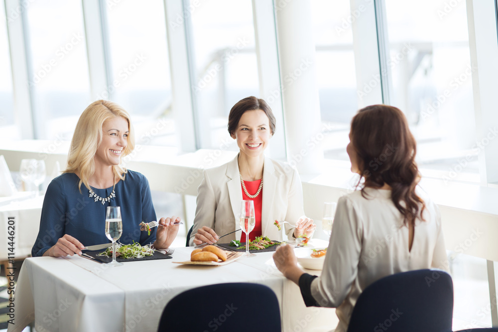 happy women eating and talking at restaurant happy women eating and talking at restaurant