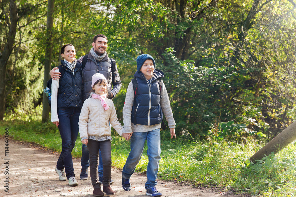 happy family with backpacks hiking in woods