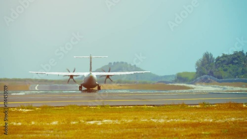 Video 4k - Small, turbo-prop communter airplane takes off from Phuket International Airport on a beautiful, sunny day, with a load of satisfied tourists. photo