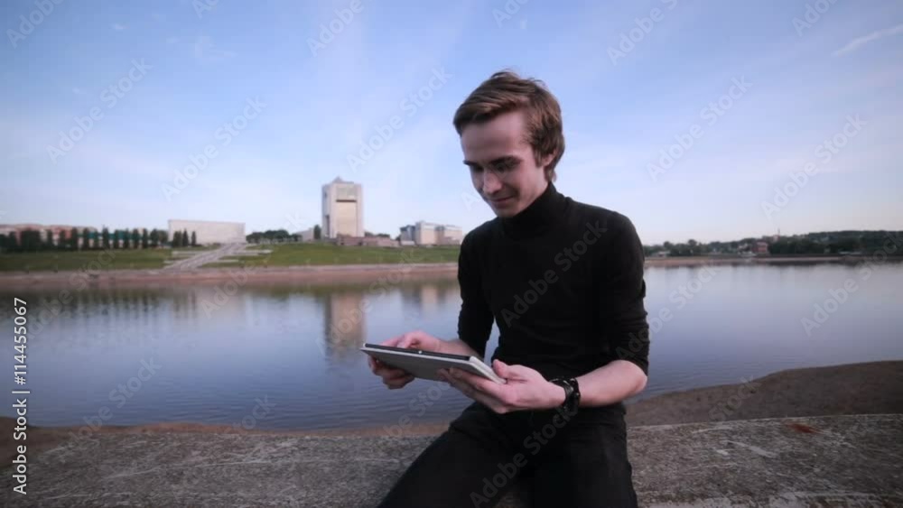 Young man getting message with tablet computer near the city lake. HD. Young man getting message with tablet computer near the city lake. HD.