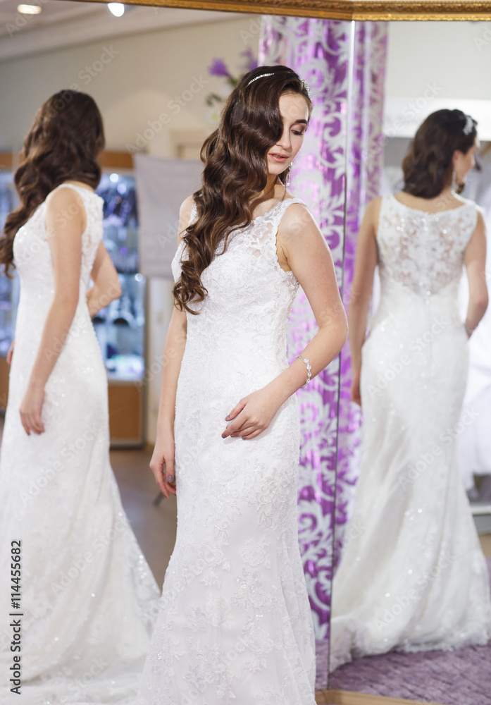 Female trying on wedding dress in a shop.