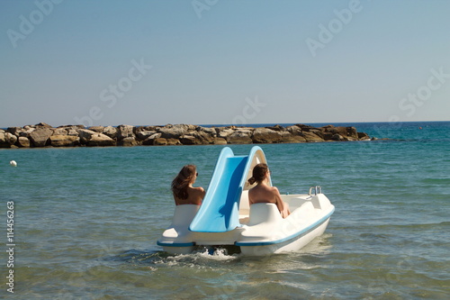 Two beautiful young women on the back on pedalo boat