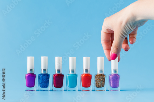 Group of bright nail polishes and woman hand