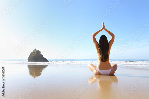 Woman exercising yoga in the beach