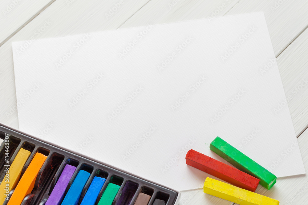 Fototapeta premium Watercolor pastel crayons and white paper sheet of sketchbook on