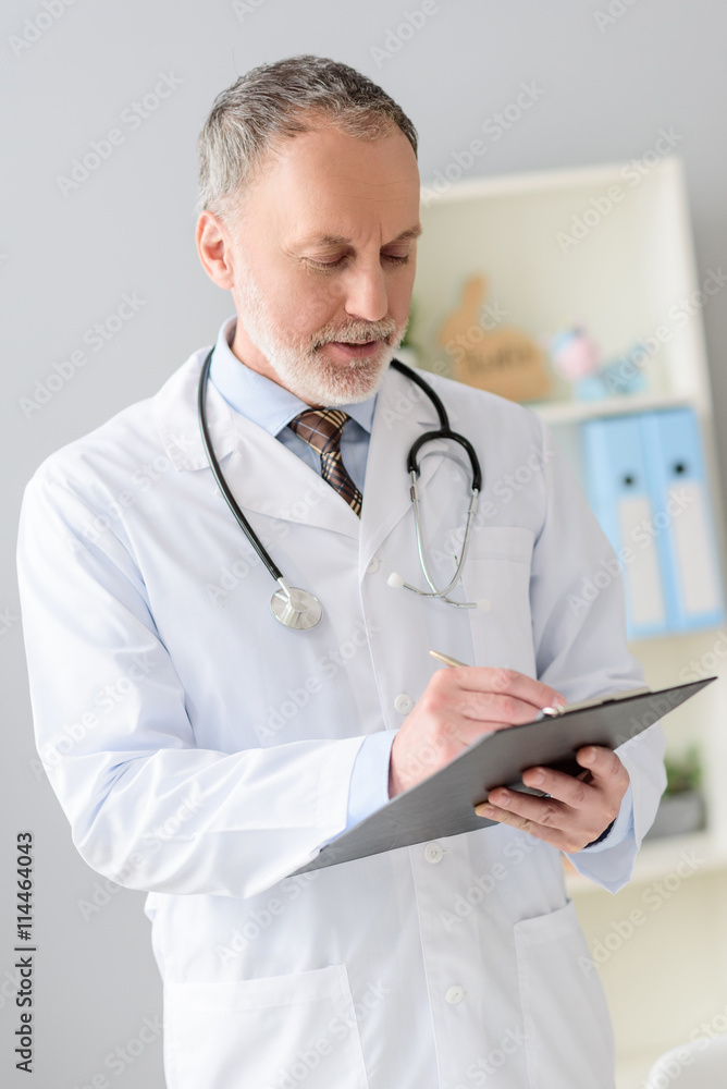 Smiling pediatrician standing at his office Smiling pediatrician standing at his office