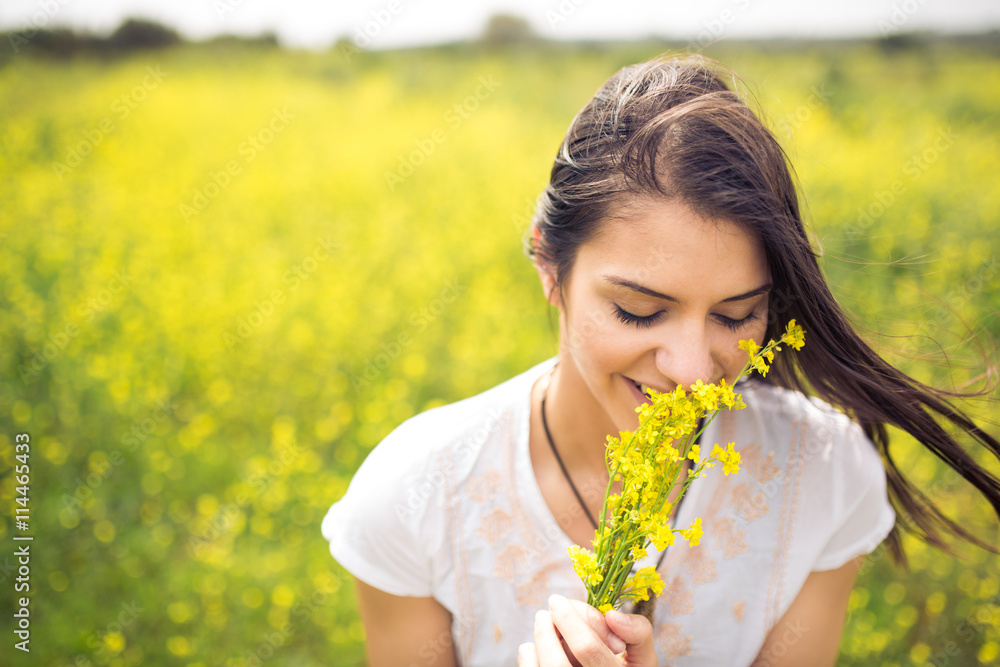Beautiful young women with flowers outdoor.Woman enjoying the scent of flowers.Gorgeous woman standing in a meadow.Perfume and aroma concept Beautiful young women with flowers outdoor.Woman enjoying the scent of flowers.Gorgeous woman standing in a meadow.Perfume and aroma concept