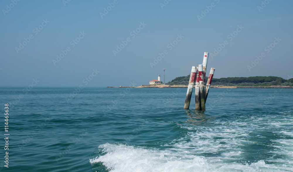 Bootswellen am Mittelmeer mit Begrenzung und Leuchtturm im Hintergrund