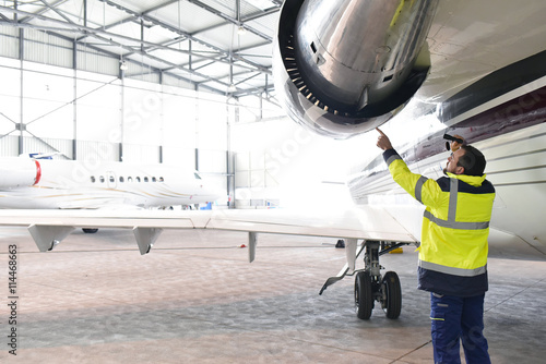 Flugzeugmechaniker kontrolliert Triebwerk eines Flugzeuges im Hangar // aircraft mechanic controlled engine of an airplane in the hangar photo